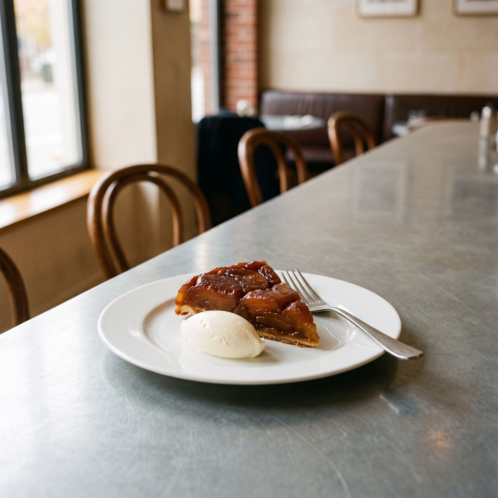 A wedge of tarte Tatin, its apples dark with caramel, crème fraîche beside it